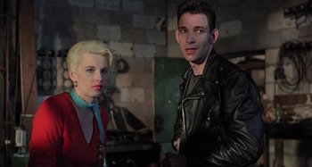 Movie still from “The Loveless” (1981), directed by Kathryn Bigelow – A man and a woman standing next to each other; Medium shot, Low angle