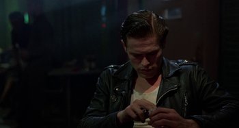 Movie still from “The Loveless” (1981), directed by Kathryn Bigelow – A man in a leather jacket is smoking a cigarette; Close Up shot, Over the shoulder angle