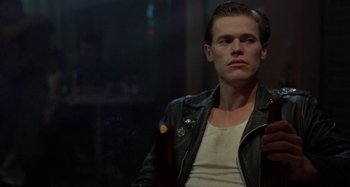 Movie still from “The Loveless” (1981), directed by Kathryn Bigelow – A man wearing a leather jacket sitting in a room; Close Up shot, Low angle