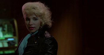Movie still from “The Loveless” (1981), directed by Kathryn Bigelow – A woman with blonde curly hair wearing a leather jacket; Close Up shot, Over the shoulder angle