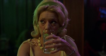 Movie still from “The Loveless” (1981), directed by Kathryn Bigelow – A woman drinking a glass of water at a party; Close Up shot, Over the shoulder angle
