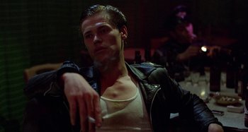 Movie still from “The Loveless” (1981), directed by Kathryn Bigelow – A young man smoking a cigarette while wearing a leather jacket; Close Up shot, Low angle