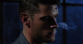 Movie still from “The Loveless” (1981), directed by Kathryn Bigelow – A person smoking a cigarette; Close Up shot, Over the shoulder angle