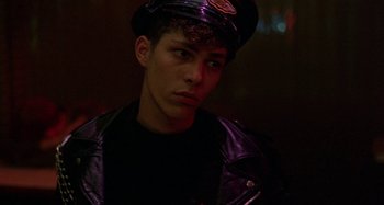 Movie still from “The Loveless” (1981), directed by Kathryn Bigelow – A young man wearing a leather jacket and hat; Close Up shot, Low angle