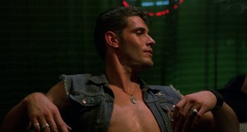 Movie still from “The Loveless” (1981), directed by Kathryn Bigelow – A man with no shirt is standing in a room; Close Up shot, Low angle