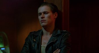 Movie still from “The Loveless” (1981), directed by Kathryn Bigelow – A man wearing a leather jacket with his arms crossed; Close Up shot, Low angle