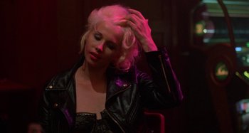 Movie still from “The Loveless” (1981), directed by Kathryn Bigelow – A woman in a black leather jacket touching her blonde hair; Close Up shot, Over the shoulder angle