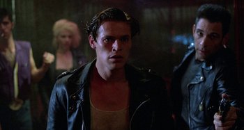 Movie still from “The Loveless” (1981), directed by Kathryn Bigelow – A man in a black leather jacket standing next to a woman; Close Up shot, Over the shoulder angle