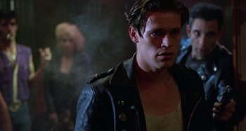 Movie still from “The Loveless” (1981), directed by Kathryn Bigelow – A man in a leather jacket looking into the distance; Close Up shot, Over the shoulder angle