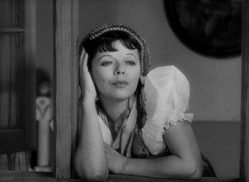 Movie still from “The Merry Widow” (1934), directed by Ernst Lubitsch – A black - and - white photo of a woman leaning against a wall; Close Up shot, High angle