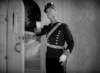 Movie still from “The Merry Widow” (1934), directed by Ernst Lubitsch – A man in a military uniform holding a gun; Medium shot, Low angle