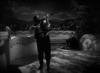 Movie still from “The Merry Widow” (1934), directed by Ernst Lubitsch – A black and white photo of a man playing a violin; Wide shot, High angle
