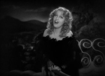 Movie still from “The Merry Widow” (1934), directed by Ernst Lubitsch – An old black and white photo of a woman smiling; Medium shot, High angle
