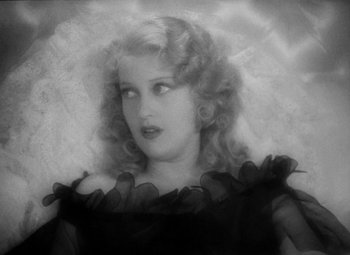 Movie still from “The Merry Widow” (1934), directed by Ernst Lubitsch – An old black and white photo of a woman in a black dress; Close Up shot, High angle
