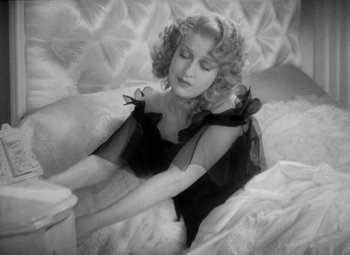 Movie still from “The Merry Widow” (1934), directed by Ernst Lubitsch – A black and white photo of a woman sitting on a couch; Medium shot, High angle