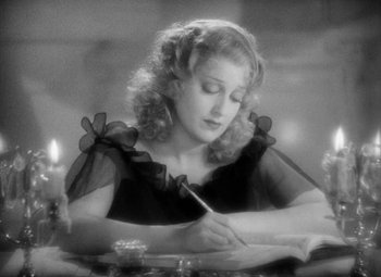Movie still from “The Merry Widow” (1934), directed by Ernst Lubitsch – A woman writing on a paper with a pen; Close Up shot, High angle