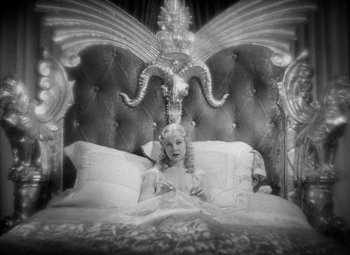 Movie still from “The Merry Widow” (1934), directed by Ernst Lubitsch – A black and white photo of a woman sitting on a bed; Medium shot, High angle