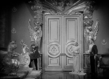 Movie still from “The Merry Widow” (1934), directed by Ernst Lubitsch – A black - and - white photo of a room with a statue of a woman; Extreme Wide shot, High angle