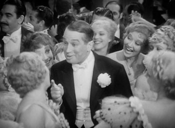Movie still from “The Merry Widow” (1934), directed by Ernst Lubitsch – A man in a tuxedo surrounded by people; Medium shot, High angle