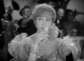 Movie still from “The Merry Widow” (1934), directed by Ernst Lubitsch – A black and white photo of a woman holding a wine glass; Close Up shot, Over the shoulder angle