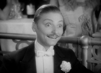 Movie still from “The Merry Widow” (1934), directed by Ernst Lubitsch – An old photo of a man in a suit and bow tie; Close Up shot, High angle