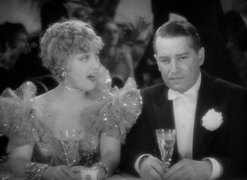 Movie still from “The Merry Widow” (1934), directed by Ernst Lubitsch – A man and a woman sitting next to each other at a table; Medium shot, High angle