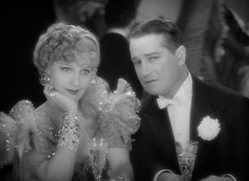 Movie still from “The Merry Widow” (1934), directed by Ernst Lubitsch – A man and a woman sitting next to each other at a table; Close Up shot, High angle