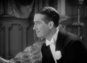 Movie still from “The Merry Widow” (1934), directed by Ernst Lubitsch – A man wearing a suit and a white flower in his hair; Close Up shot, High angle