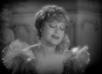 Movie still from “The Merry Widow” (1934), directed by Ernst Lubitsch – An old black and white photo of a woman in a dress; Close Up shot, High angle