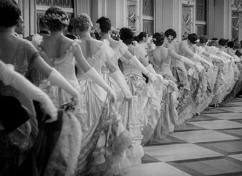 Movie still from “The Merry Widow” (1934), directed by Ernst Lubitsch – A group of women in long dresses are standing in a line; Wide shot, Low angle