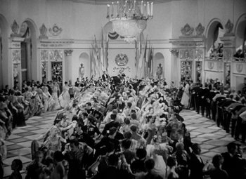 Movie still from “The Merry Widow” (1934), directed by Ernst Lubitsch – A large group of people gathered in a large room; Extreme Wide shot, High angle