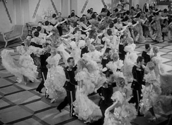 Movie still from “The Merry Widow” (1934), directed by Ernst Lubitsch – A large group of people dancing in a room; Wide shot, High angle