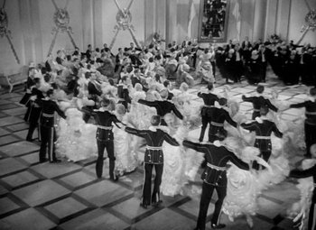 Movie still from “The Merry Widow” (1934), directed by Ernst Lubitsch – A black and white photo of a group of men and women dancing; Extreme Wide shot, High angle