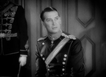 Movie still from “The Merry Widow” (1934), directed by Ernst Lubitsch – A black and white photo of a man in a military uniform; Close Up shot, Over the shoulder angle