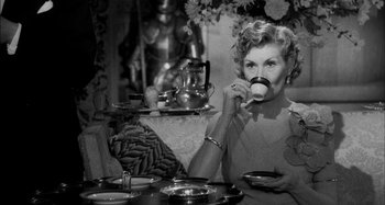 Movie still from “The Mirror Crack'd” (1980), directed by Guy Hamilton – An older woman sitting at a table drinking a cup of tea; Medium shot, High angle