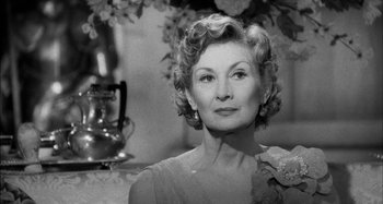 Movie still from “The Mirror Crack'd” (1980), directed by Guy Hamilton – An older woman in a dress is posing for a picture; Close Up shot, Low angle