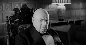 Movie still from “The Mirror Crack'd” (1980), directed by Guy Hamilton – An older bald man in a tuxedo sitting in a chair; Close Up shot, Low angle