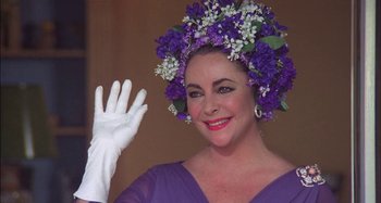 Movie still from “The Mirror Crack'd” (1980), directed by Guy Hamilton – A person wearing gloves and a flower crown; Close Up shot, Over the shoulder angle