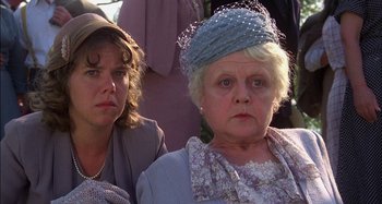 Movie still from “The Mirror Crack'd” (1980), directed by Guy Hamilton – Two people sitting next to each other wearing hats; Close Up shot, Low angle