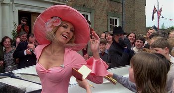 Movie still from “The Mirror Crack'd” (1980), directed by Guy Hamilton – A woman in a pink dress and a pink hat; Medium shot, Low angle