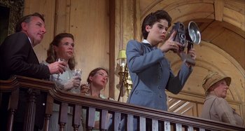 Movie still from “The Mirror Crack'd” (1980), directed by Guy Hamilton – A woman taking a picture with a cell phone while two other women watch; Medium shot, Low angle