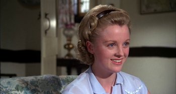 Movie still from “The Mirror Crack'd” (1980), directed by Guy Hamilton – A woman with blonde curly hair wearing a blue shirt; Close Up shot, Over the shoulder angle