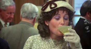 Movie still from “The Mirror Crack'd” (1980), directed by Guy Hamilton – A woman wearing a hat drinking from a wine glass; Close Up shot, High angle