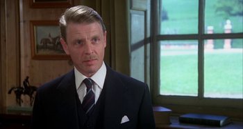 Movie still from “The Mirror Crack'd” (1980), directed by Guy Hamilton – A person wearing a suit and tie; Close Up shot, Over the shoulder angle