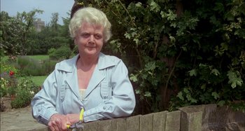 Movie still from “The Mirror Crack'd” (1980), directed by Guy Hamilton – An older woman standing next to a wooden fence; Close Up shot, Low angle