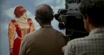 Movie still from “The Mirror Crack'd” (1980), directed by Guy Hamilton – A man is filming a woman in a medieval dress; Medium shot, Over the shoulder angle