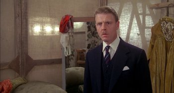 Movie still from “The Mirror Crack'd” (1980), directed by Guy Hamilton – A man in a suit and tie standing in front of a mirror; Close Up shot, Over the shoulder angle