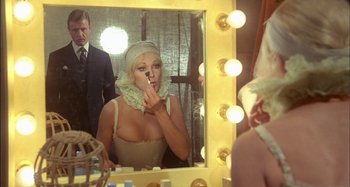 Movie still from “The Mirror Crack'd” (1980), directed by Guy Hamilton – A woman is putting lipstick on in a mirror; Medium shot, Over the shoulder angle