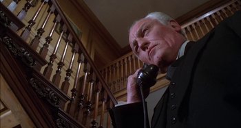Movie still from “The Mirror Crack'd” (1980), directed by Guy Hamilton – An older man talking on a phone in front of a staircase; Close Up shot, Low angle