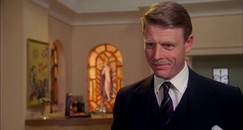 Movie still from “The Mirror Crack'd” (1980), directed by Guy Hamilton – A person wearing a suit and tie; Close Up shot, Low angle